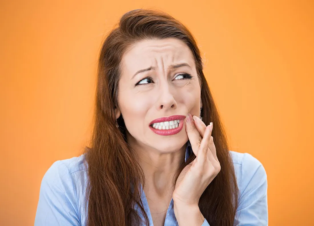 Woman with tooth pain holding her cheek