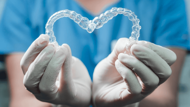 Dentist holding Invisalign clear aligners in Elk Grove village Illinois